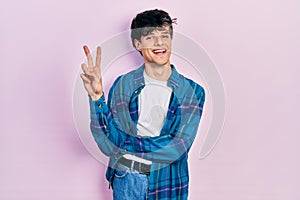 Handsome hipster young man wearing casual white t shirt and vintage shirt smiling with happy face winking at the camera doing