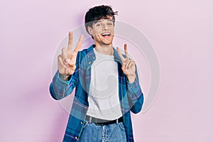 Handsome hipster young man wearing casual white t shirt and vintage shirt smiling looking to the camera showing fingers doing