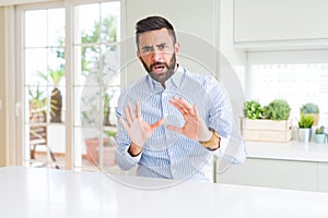 Handsome hispanic business man afraid and terrified with fear expression stop gesture with hands, shouting in shock