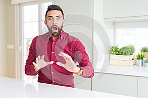 Handsome hispanic business man afraid and terrified with fear expression stop gesture with hands, shouting in shock