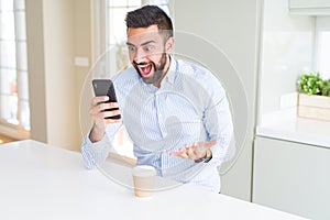 Handsome hispanic business man drinking coffee and using smartphone very happy and excited, winner expression celebrating victory