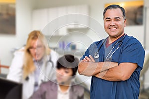 Handsome Hispanic Doctor or Nurse Standing in His Office with Staff Working Behind