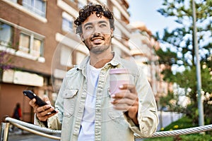 Handsome hispanic man with beard smiling happy outdoors on a sunny day using smartphone