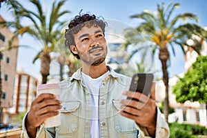 Handsome hispanic man with beard smiling happy outdoors on a sunny day using smartphone