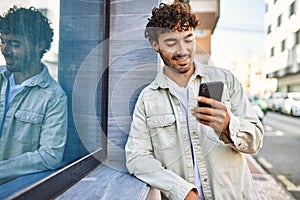 Handsome hispanic man with beard smiling happy outdoors on a sunny day using smartphone