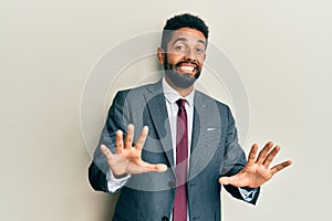 Handsome hispanic man with beard wearing business suit and tie afraid and terrified with fear expression stop gesture with hands,