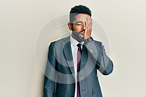 Handsome hispanic man with beard wearing business suit and tie yawning tired covering half face, eye and mouth with hand