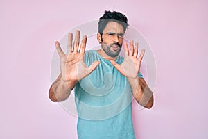Handsome hispanic man with beard wearing casual clothes afraid and terrified with fear expression stop gesture with hands,