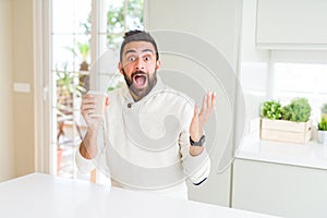 Handsome hispanic man drinking a coffee in a paper cup very happy and excited, winner expression celebrating victory screaming