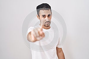 Handsome hispanic man standing over white background pointing with finger up and angry expression, showing no gesture