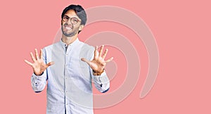 Handsome hispanic man wearing business shirt and glasses afraid and terrified with fear expression stop gesture with hands,