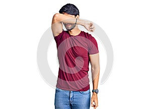 Handsome hispanic man wearing casual clothes covering eyes with arm, looking serious and sad