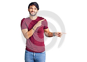 Handsome hispanic man wearing casual clothes pointing aside worried and nervous with both hands, concerned and surprised