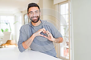 Handsome hispanic man wearing casual sweatshirt at home smiling in love showing heart symbol and shape with hands