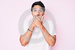 Handsome hispanic man wearing casual white tshirt shocked covering mouth with hands for mistake