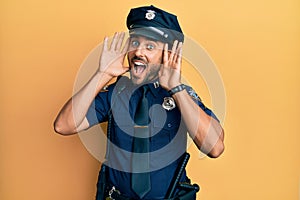 Handsome hispanic man wearing police uniform smiling cheerful playing peek a boo with hands showing face