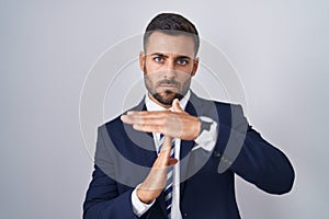 Handsome hispanic man wearing suit and tie doing time out gesture with hands, frustrated and serious face