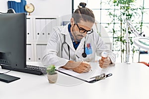 Handsome hispanic man working as doctor writing pills presciption at hospital clinic