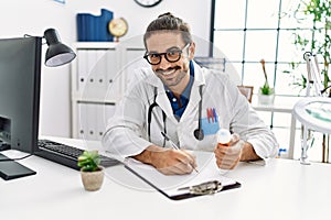 Handsome hispanic man working as doctor writing pills presciption at hospital clinic