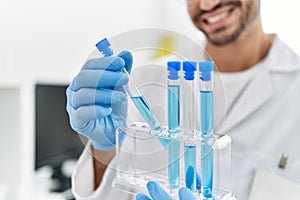 Handsome hispanic man working as scientific holding test tubes at laboratory