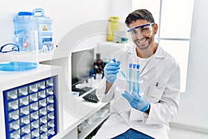 Handsome hispanic man working as scientific holding test tubes at laboratory