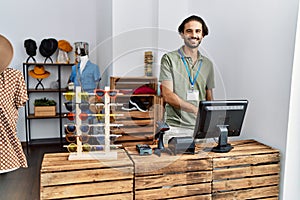 Handsome hispanic man working as shop assistance at retail shop