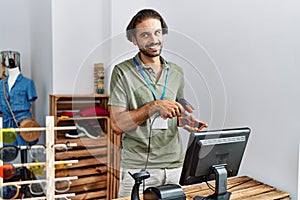 Handsome hispanic man working at shop using barcode scanner at retail shop