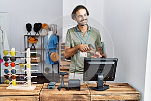 Handsome hispanic man working at shop using barcode scanner at retail shop