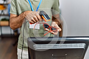 Handsome hispanic man working at shop using barcode scanner at retail shop