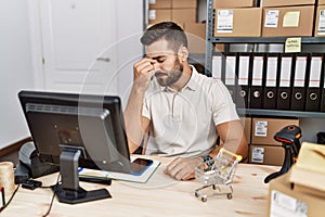 Handsome hispanic man working at small business commerce tired rubbing nose and eyes feeling fatigue and headache