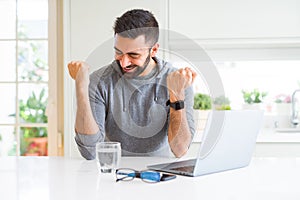 Handsome hispanic man working using computer laptop very happy and excited doing winner gesture with arms raised, smiling and