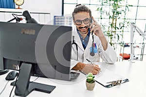 Handsome hispanic man writing presciption on the phone at hospital clinic