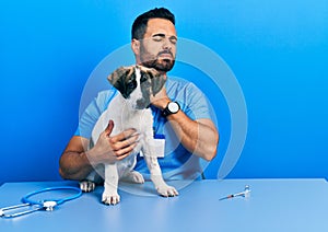 Handsome hispanic veterinary man with beard checking dog health touching painful neck, sore throat for flu, clod and infection