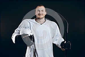 Handsome hockey player. Smiling at camera isolated on black background.