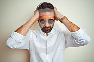 Handsome indian buinessman wearing shirt and sunglasses over isolated white background suffering from headache desperate and