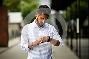 Handsome indian businessman checking time on his watch