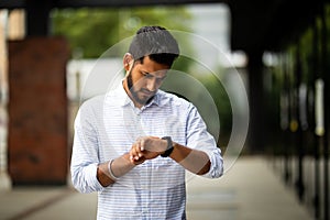 Handsome indian businessman checking time on his watch