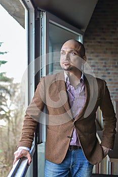 Handsome indian businessman, standing near panoramic window, thinking,