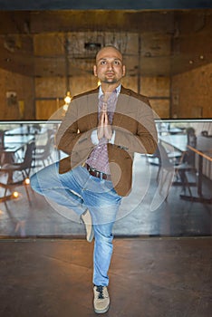 Handsome indian businessman weared in suit performing yoga or asana to relax, smiling lloking at camera photo