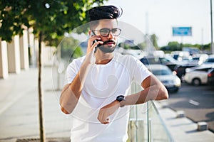 Handsome indian man cell phone call smile outdoor city street. Young attractive businessman casual blue shirt talking