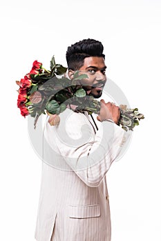 Handsome indian man holding bouquet of red roses, isolated on white background
