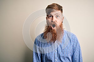 Handsome Irish redhead business man with beard standing over isolated background afraid and shocked with surprise expression, fear