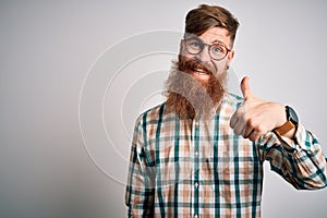 Handsome Irish redhead man with beard wearing glasses and hipster shirt doing happy thumbs up gesture with hand