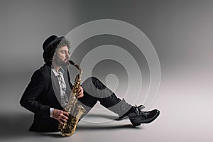 handsome jazzman playing saxophone while sitting