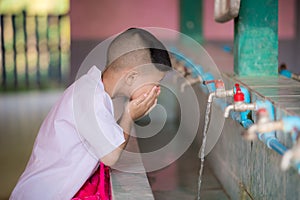 Handsome kid boy use their hands to clean water from their faucets and wash their faces after a run in the hot sun.