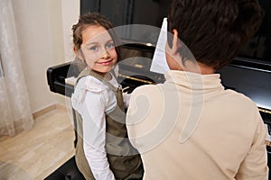 Handsome kids pianists playing grand piano, smiling looking at the camera. People. Culture. Arts. Education