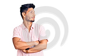 Handsome latin american young man wearing casual summer shirt looking to the side with arms crossed convinced and confident