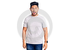 Handsome latin american young man wearing casual tshirt winking looking at the camera with sexy expression, cheerful and happy