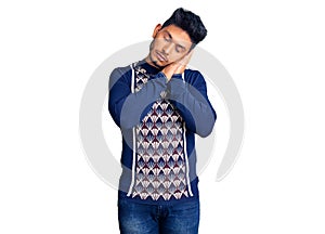 Handsome latin american young man wearing casual winter sweater sleeping tired dreaming and posing with hands together while