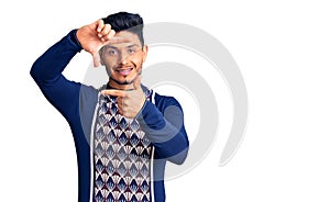 Handsome latin american young man wearing casual winter sweater smiling making frame with hands and fingers with happy face